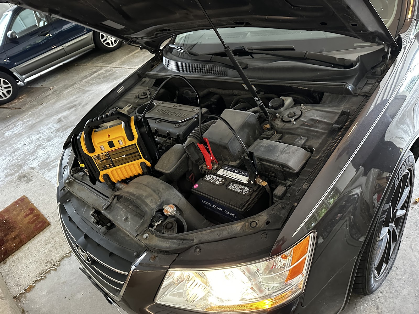 Battery booster connected under a car hood